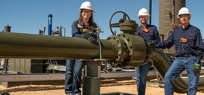 Workers standing next to a pipe