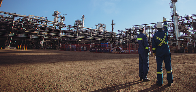 Two workers pointing at pipes in a facility